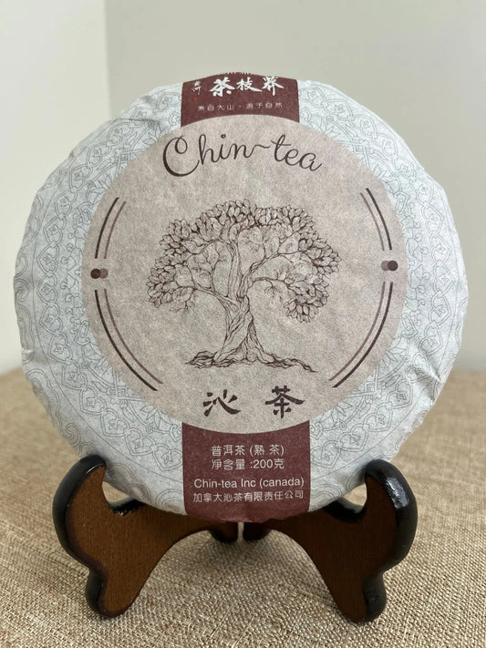 Award-winning fermented Pu-erh tea cake (Shou Pu-erh) from the Chin-tea Signature Collection displayed on a traditional wooden tea stand