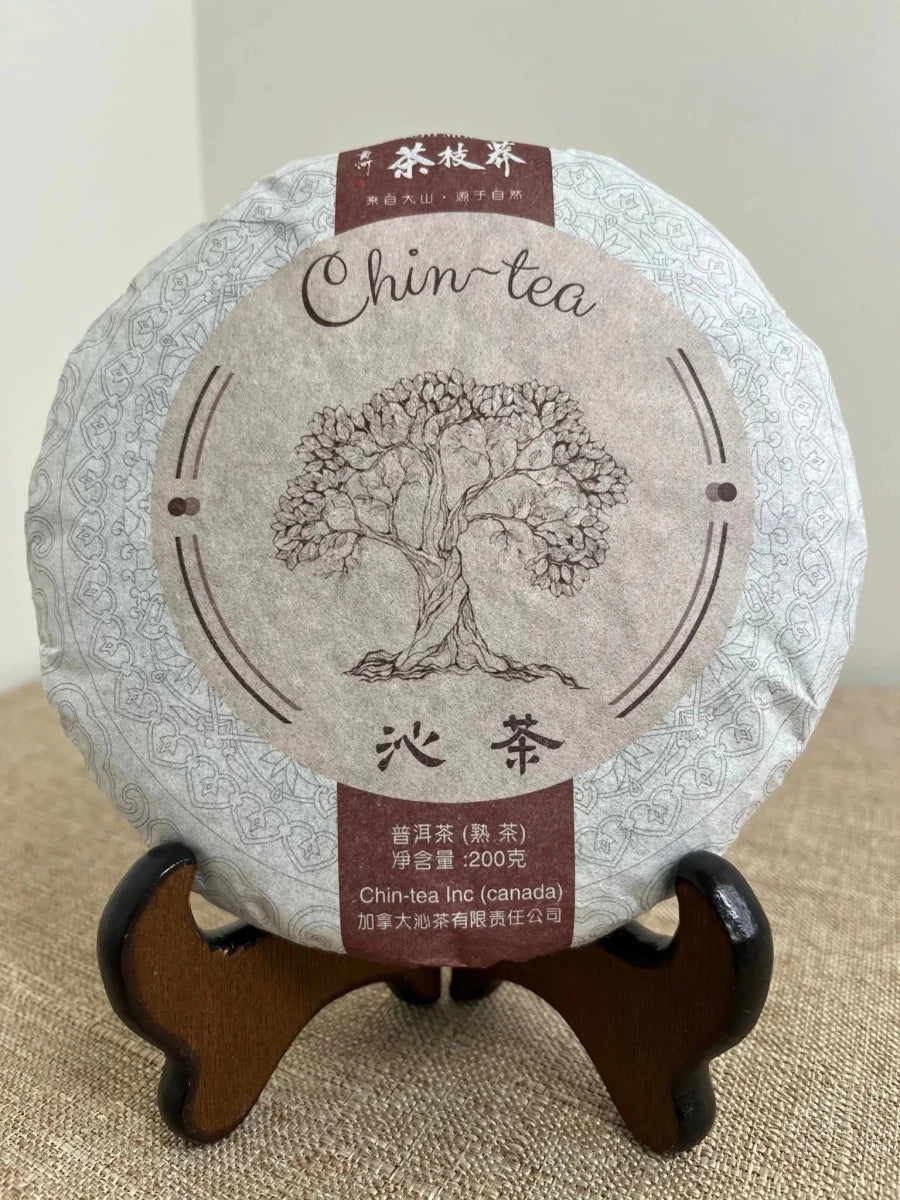 Award-winning fermented Pu-erh tea cake (Shou Pu-erh) from the Chin-tea Signature Collection displayed on a traditional wooden tea stand